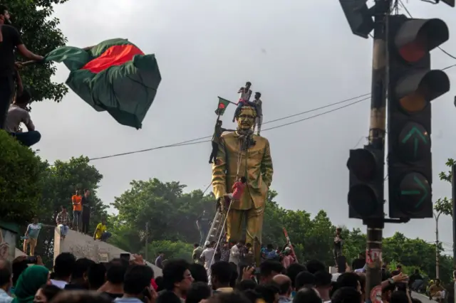 Jóvenes sobre la estatua a Sheikh Mujibur Rahman en Daca