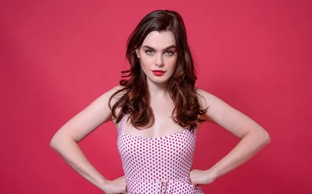 Charli wearing a polka dot dress, shocking pink background