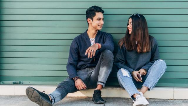 Dois jovens sentados lado a lado se olhamvalsports net apostasmaneira interessada