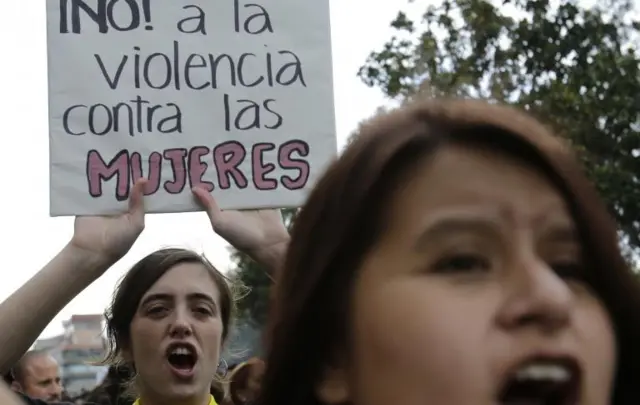Una mujer sostiene un cartel con la leyenda "No a la violencia contra las mujeres".