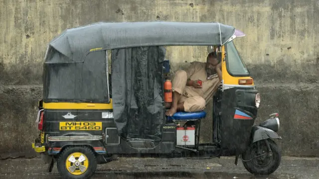 स्मार्टफ़ोन यूज़ करता ऑटो ड्राइवर