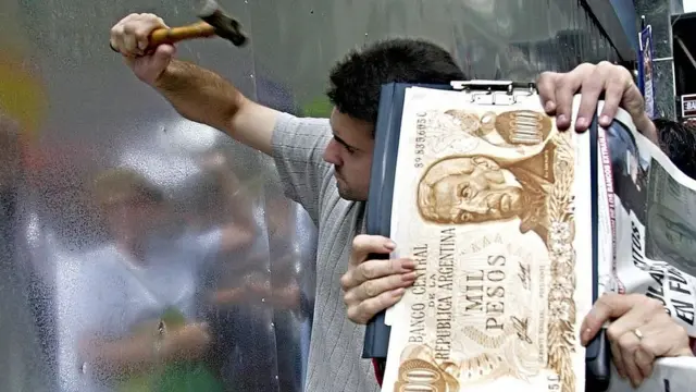 Joven en Argentina amartillando la puerta a un banco durante la crisis de el corralito.