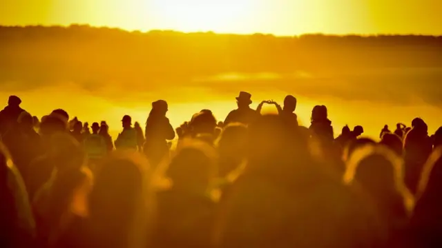 People turn to face the rising sun at Stonehenge where people gather to celebrate the dawn of the longest day in the UK. PRESS ASSOCIATION Photo. Picture date: Friday June 21, 2019.