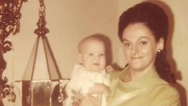 Жінка з довгим темним волоссям тримає на руках немовля