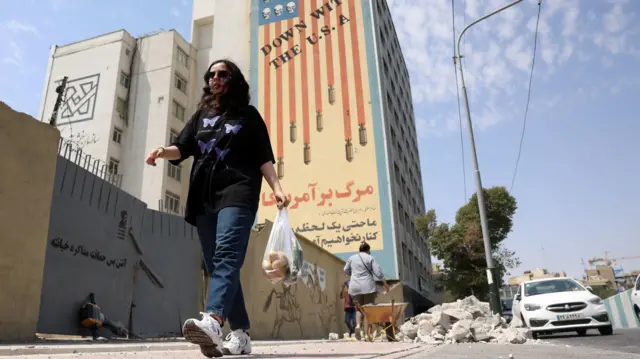 امرأة إيرانية تمر أمام جدارية مناهضة للولايات المتحدة في طهران، إيران، في 17 أغسطس/آب 2026.