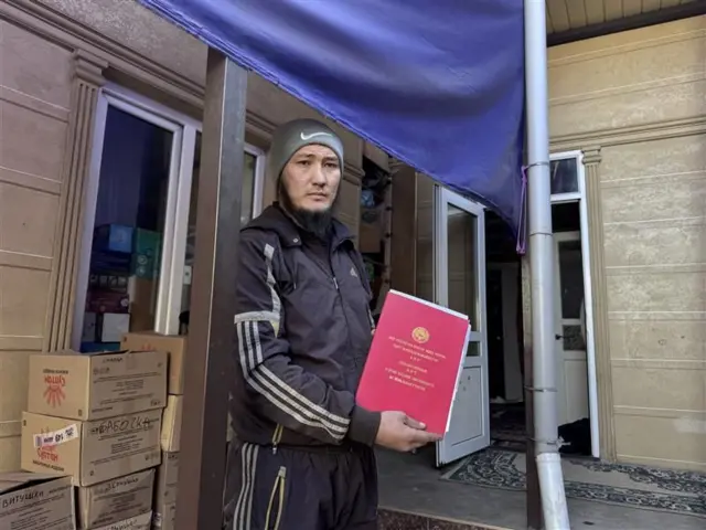 Мухаммадюсуф Иминжанов үйүнүн кызыл китебин кармап турат. 
