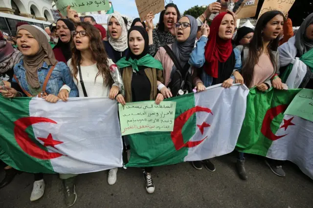 معترضان الجزایری در جریان تظاهرات ضد دولتی در الجزیره، الجزایر، ۱۰ مارس ۲۰۲۰، راهپیمایی می‌کنند. الجزایری‌ها از زمان آغاز اعتراض‌ها در ۱۶ فوریه ۲۰۱۹، پس از اعلام نامزدی عبدالعزیز بوتفلیقه برای پنجمین دوره ریاست‌جمهوری، هر هفته به اعتراض‌های خود ادامه داده‌اند.
