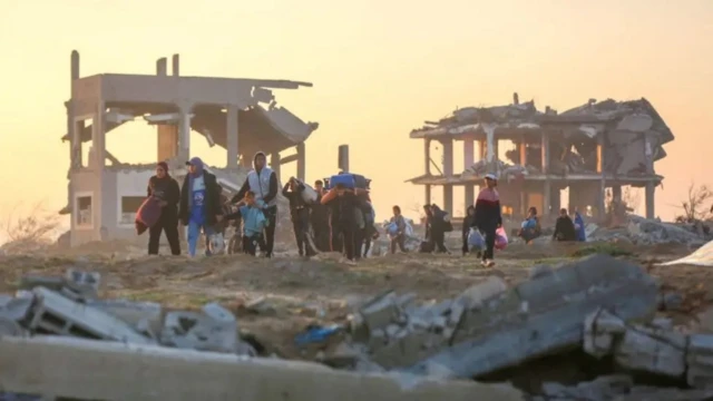 Беженцы идут мимо развалин