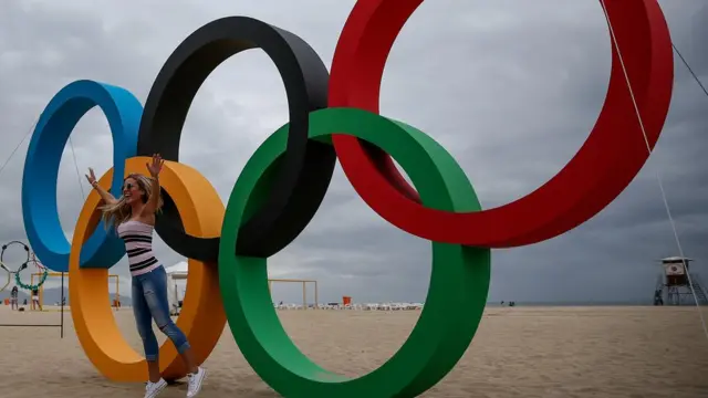 Una mujer posa frente a unos anillos olímpicos en una playa de Río de Janeiro.