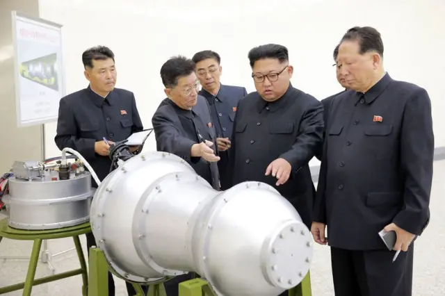 Kim Jong Un,  rodeado de cinco funcionarios norcoreanos observan el revestimiento metálico de lo que aparenta ser una bomba