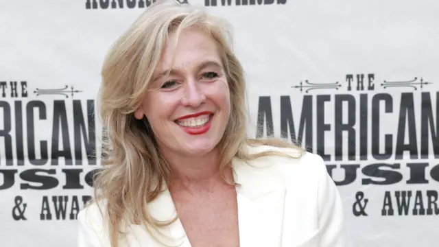 Tift Merritt no tapete vermelho de uma cerimônia de premiação em Nashville, Tennessee. Sorrindo, com cabelo loiro, ela usa uma jaqueta branca.