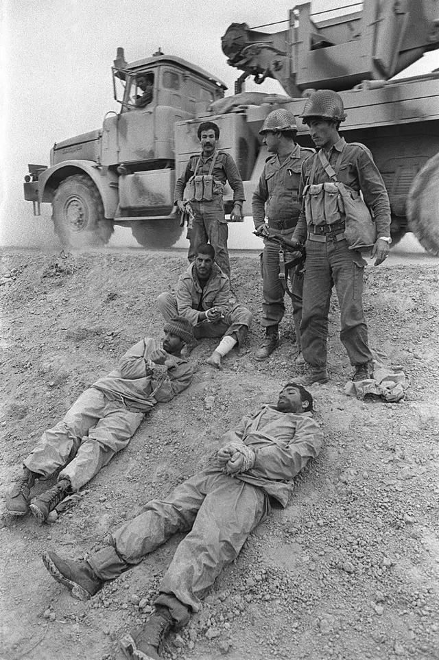 Tentara Irak mengawasi para tawanan tentara Iran yang ditangkap di garis depan, di sebelah tenggara Sungai Tigris, pada 18 Maret 1985 selama Perang Irak–Iran.