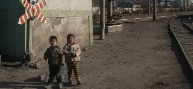 In a photo taken on November 21, 2017, children stand besides a railway track in the industrial city of Chongjin on North Korea's northeast coast.