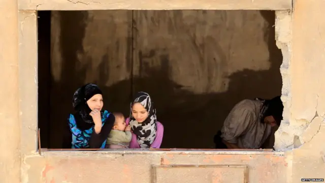 Syrian girls look out of the window of a damaged building in Douma on the outskirts of Damascus on April 16, 2018 during an organised media tour after the Syrian army declared that all anti-regime forces have left Eastern Ghouta