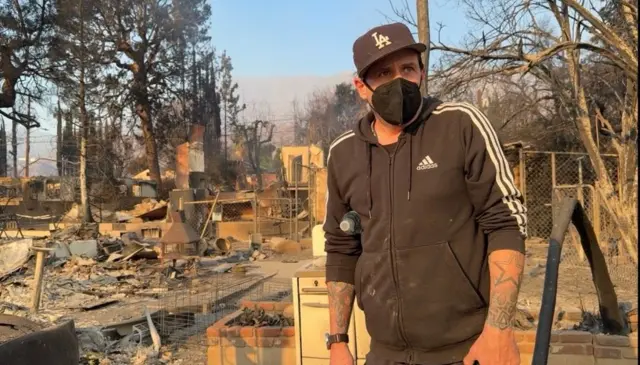 Daron sanye da baƙar riga yana zagaye a wajen da gobara ta yi ɓarna.