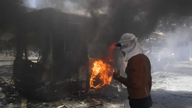 Pendukung oposisi Juan Guaido berdiri di samping sebuh bus yang terbakar di Caracas