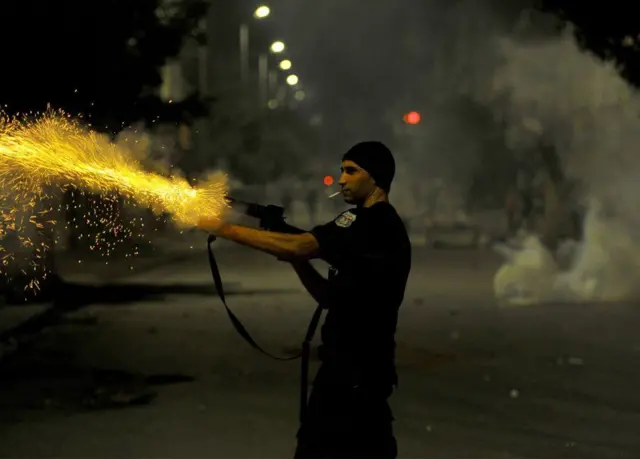 A policeman fires towards protesters in Ettadhamen, a working-class suburb in the Tunisian capital on Friday...