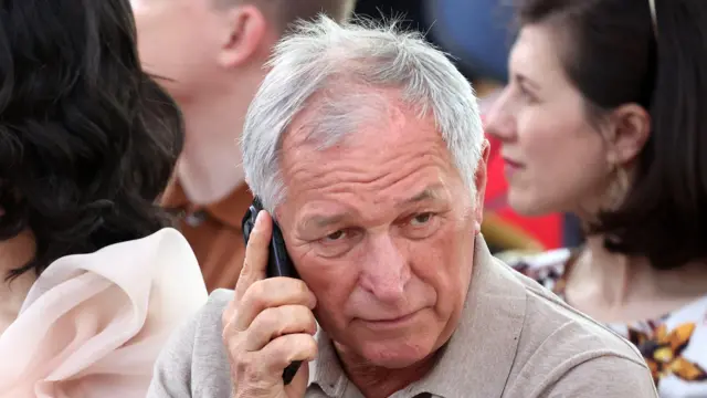 Седой мужчина разговаривает по телефону