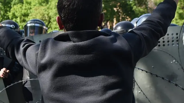 A protester holds up his hands in front of a police barricade in the Armenia capital of Yerevan