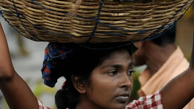 A Sri Lankan woman carries a basket of plantains at a market in Colombo on July 1, 2008.