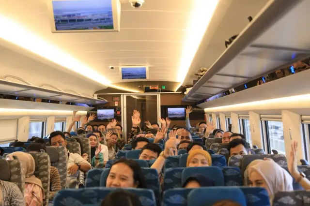 Suasana di dalam gerbong kereta cepat ketika transportasi itu baru dibuka secara komersial pada 17 Oktober 2023. Foto memperlihatkan setengah gerbong kereta. Terlihat beberapa penumpang melambaikan tangan.