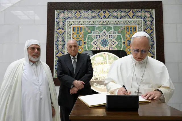 Le pape Léon XIV, accueilli par le recteur de la mosquée, Mohamed Mamoun al-Qasim, signe le Livre d'or lors de sa visite à la Grande Mosquée d'Alger le 13 avril 2026 à Alger, en Algérie. 