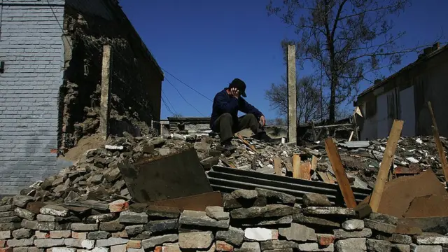 A worker takes a break at a construction site on a street made by demolishing old houses on March 4, 2008 in Beijing, China.