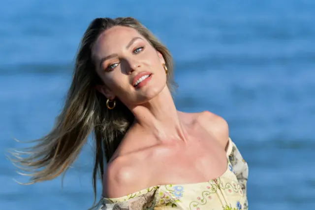 Candice Swanepoel leans her head to the side as she poses next to open water.