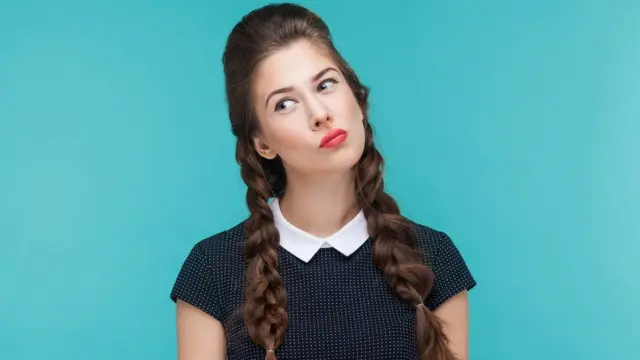 Close-up portrait of a thoughtful woman looking up, over a turquoise background.