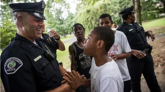 Um policial e um menino se cumprimentam