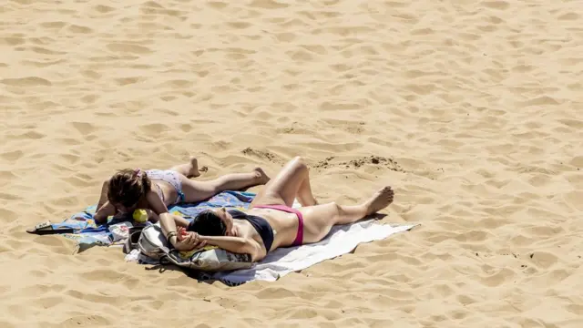 Mujeres broncéandose sobre la arena