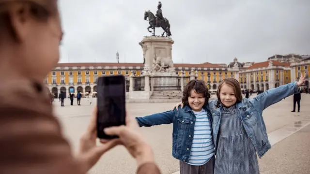 Una mujer toma una foto a sus hijos en la plaza del Comercio de Lisboa.