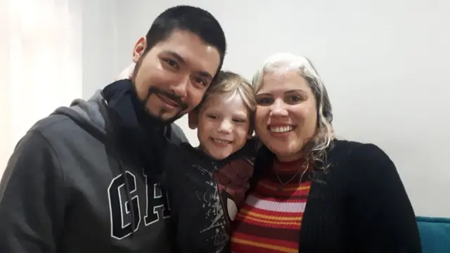 Daiana, o filho Anthony e o pai dele, Cássio Suzuki. Mãe e filho nasceram com fios brancos na região frontal do couro cabeludo e diversas manchas claras na pele. As características são causadas pelo piebaldismo, doença genética que afeta a pigmentação da pele.