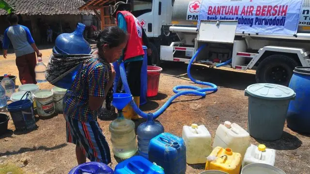 Warga menggendong galon berisi air bersih