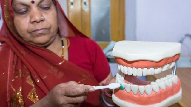 Una profesional dental demuestra cómo angular el cepillo contra los dientes