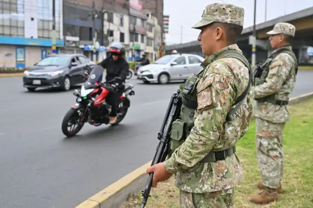 Dois militares armados montam guarda no acostamento de uma avenida no Peru