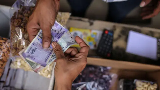 Customers holds rupee banknotes at a grocery store in Mumbai, India, on Saturday, Jan. 7, 2023. India is scheduled to release consumer price index (CPI) figures on Jan. 12. Photographer: Dhiraj Singh/Bloomberg via Getty Images