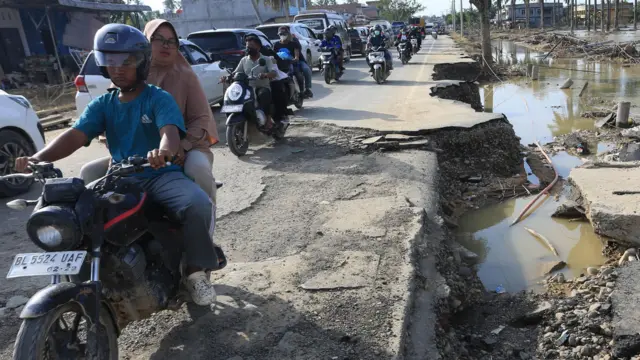 Sejumlah kendaraan antre melintasi Jalan Lintas Nasional Medan-Banda Aceh yang rusak akibat banjir di Desa Tualang Baro, Kecamatan Manyak Payed, Aceh Tamiang, Aceh, Kamis (4/12/2025).