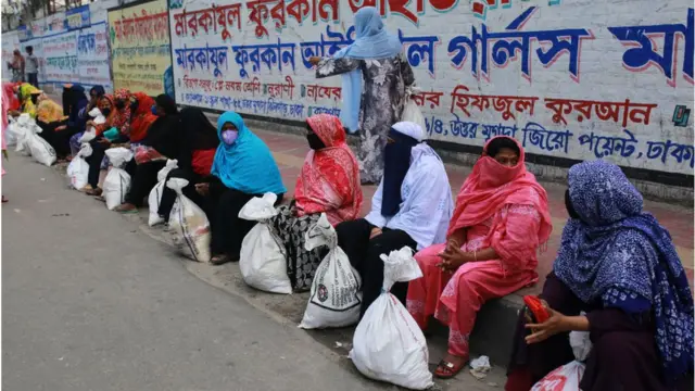 ত্রাণ সংগ্রহের পর নারীরা ফুটপাতে বসে আছেন
