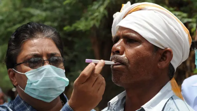 An Indian doctor examines the temperature of a villager