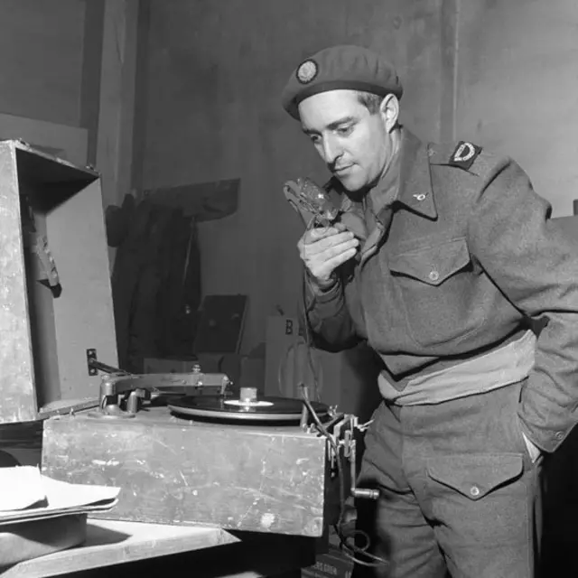 Francis Hallawell con un micrófono grabando un reportaje en un disco de pasta