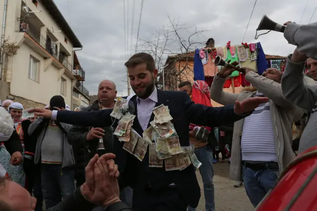 Nakićen novčanicama leva i evra, Raihan se veseli uz zvuke tupana i zurli.