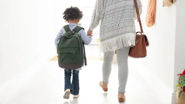 Niño camina de la mano con la mujer.