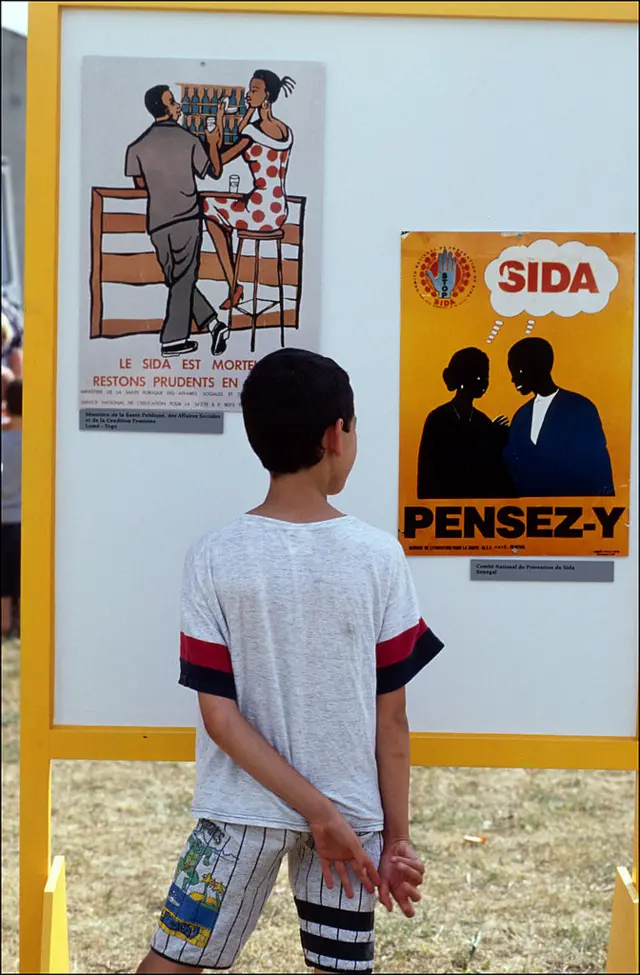 Un enfant devant une affiche de sensibilisation contre le SIDA
