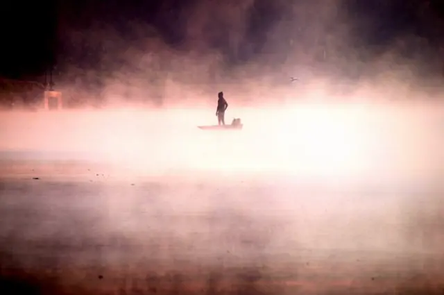 Un hombre en su barco en medio de la niebla