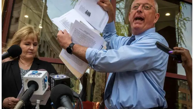 Dave Lorenz muestra el informe en una conferencia de prensa.