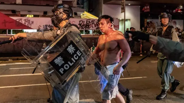 La policía escolta a un hombre que fue golpeado por los manifestantes.