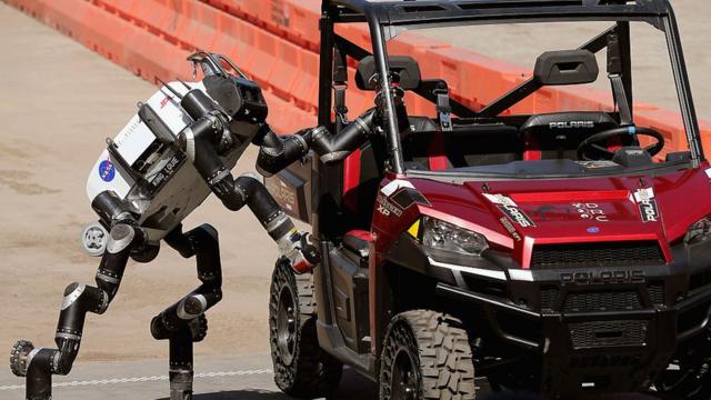 A robot climbs out of a Polaris vehicle after driving through obstacles during a show by the Pentagon's Defense Advanced Research Projects Agency (DARPA), June 2015