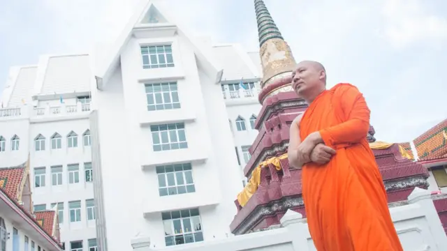 พระมหาอดิศักดิ์ อภิปัญโญ ผู้ช่วยเจ้าอาวาสวัดบรมสถล (วัดดอน) ยืนอยู่หน้าวิหารปฎิบัติธรรม