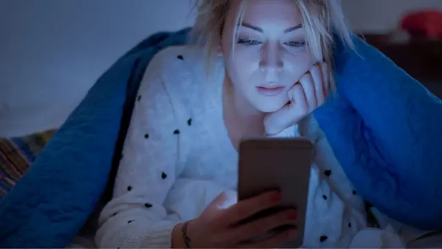 Mujer con celular en la cama